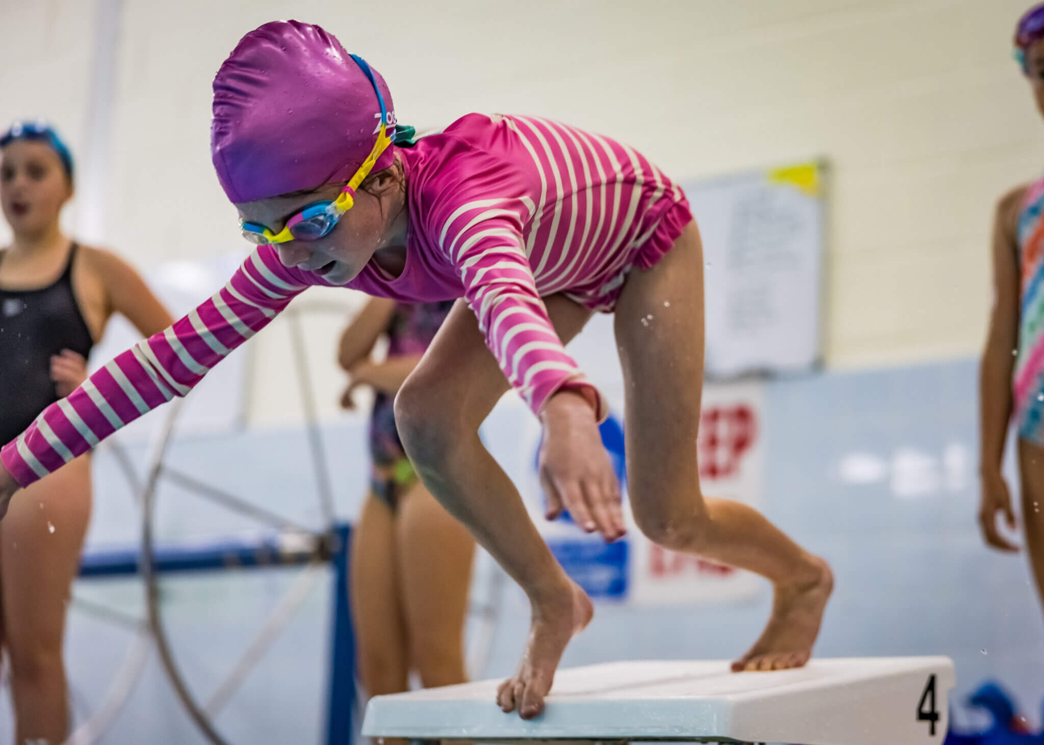 Child in pink swimwear jumping into pool