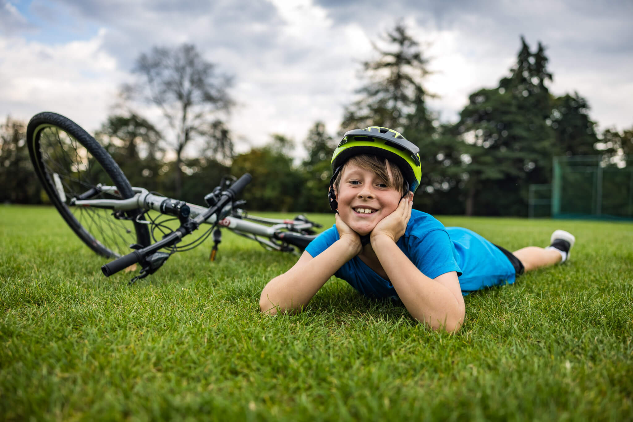 Child lying on grass next to bicycle