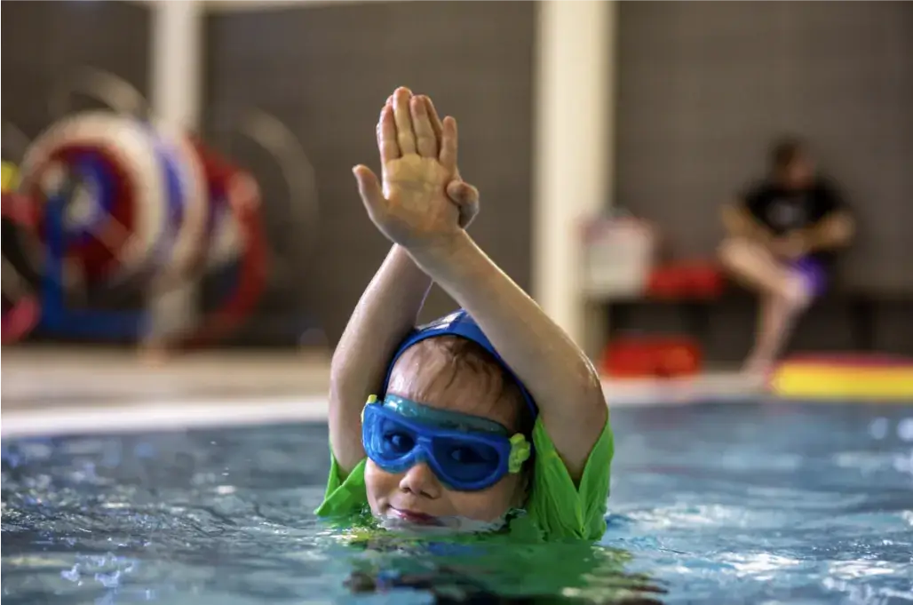 child in pool hands up